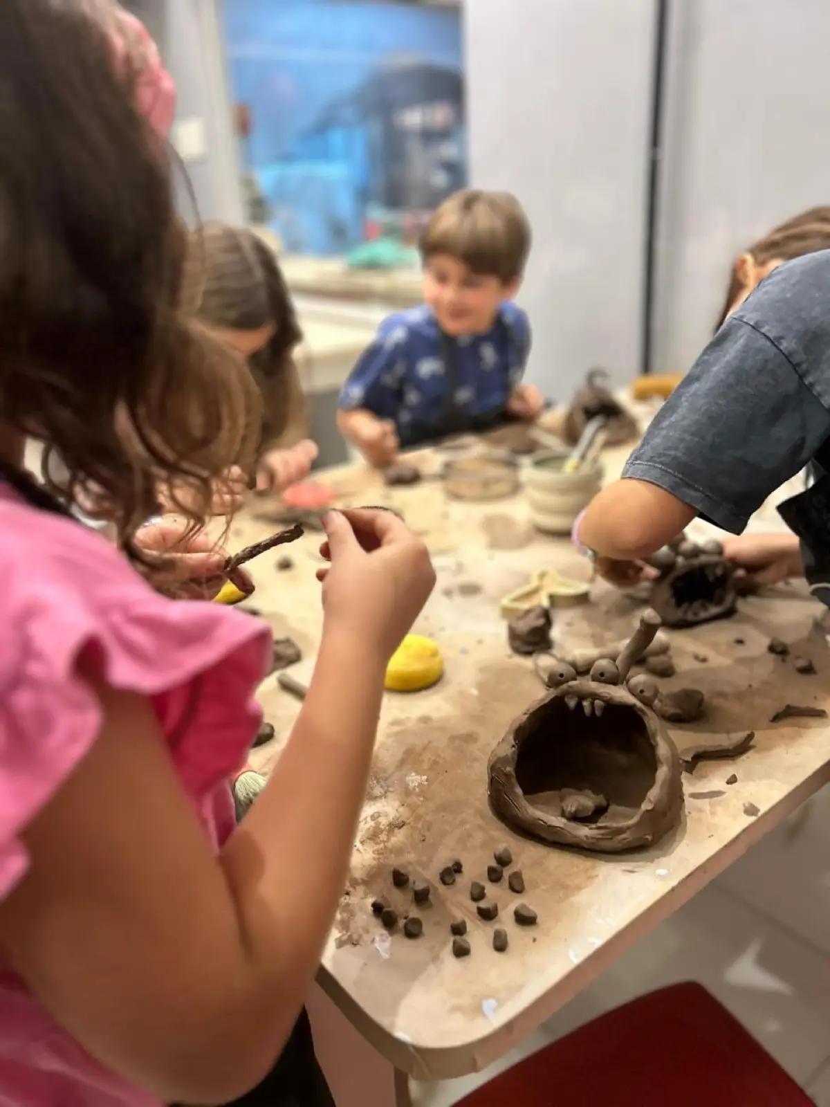 Crianças modelando argila durante uma aula da MUD.